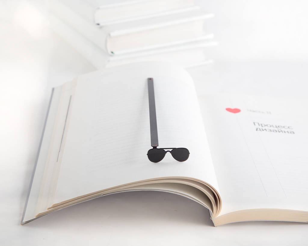 Police Sunglasses metal bookmark resting on the pages of an open book