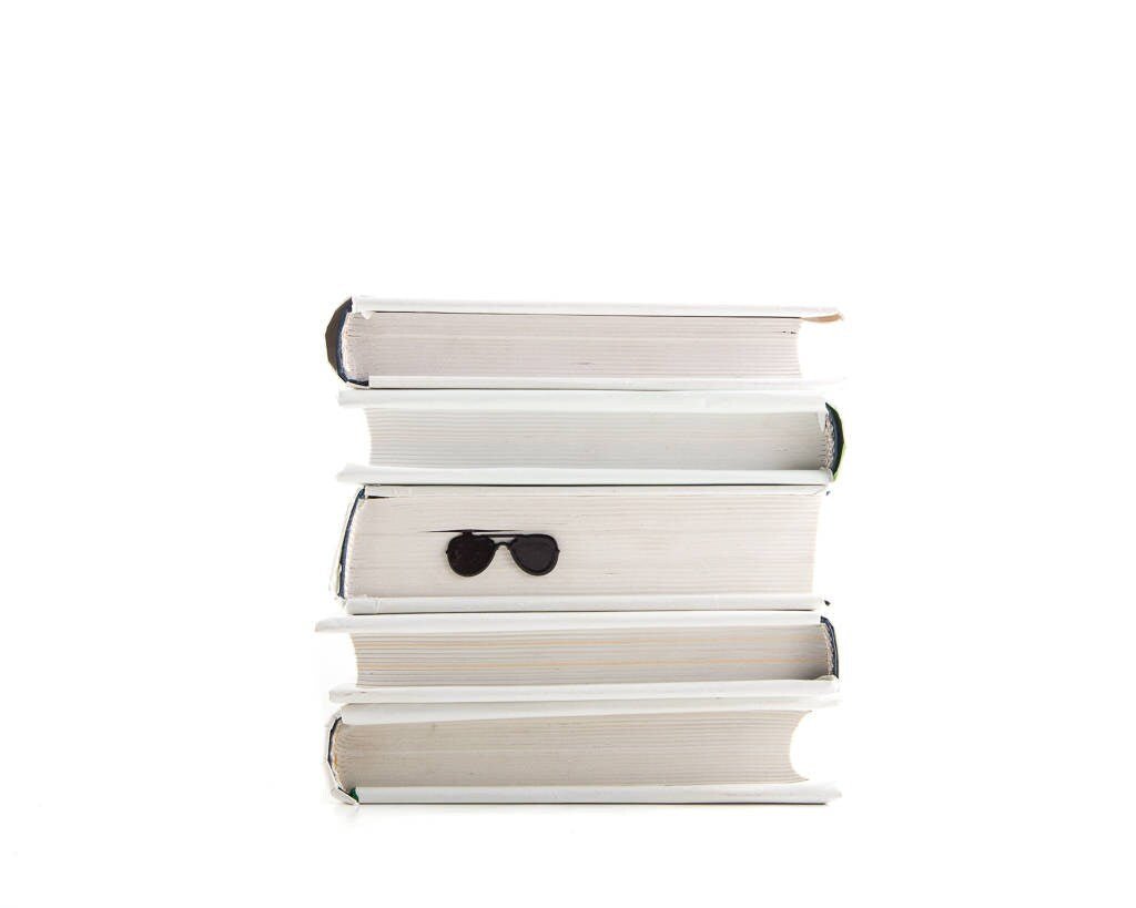 Police Sunglasses metal bookmark shown with a stack of books