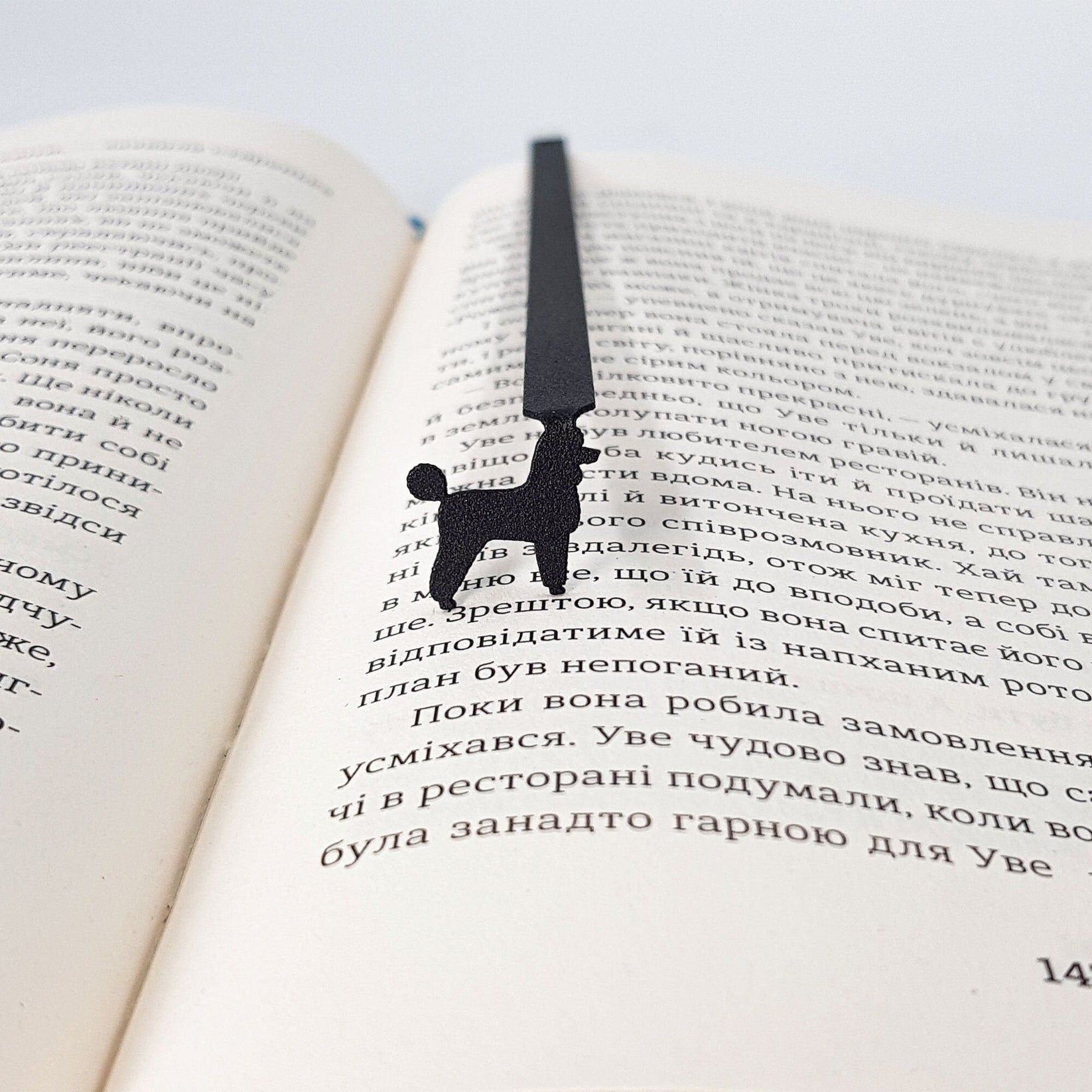 Poodle metal bookmark marking a page in an open book