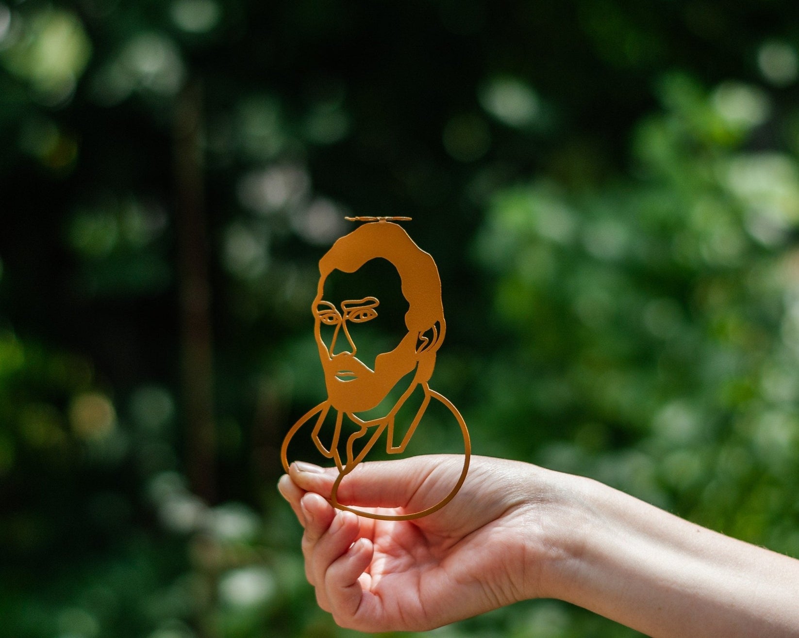Van Gogh Portrait metal bookmark in gold held up beside an open book