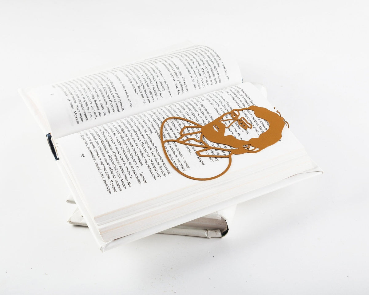 Van Gogh Portrait metal bookmark in gold lying across the pages of an open book