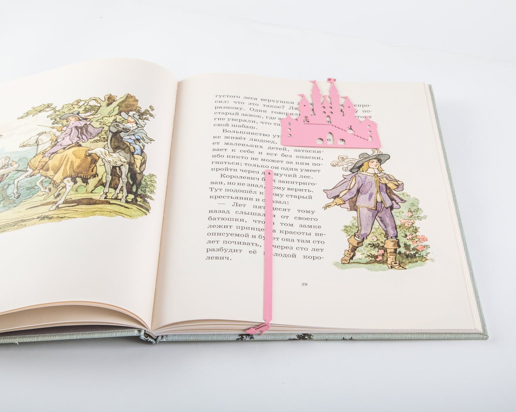 Princess Castle in Pink metal bookmark in red marking a page in an open book
