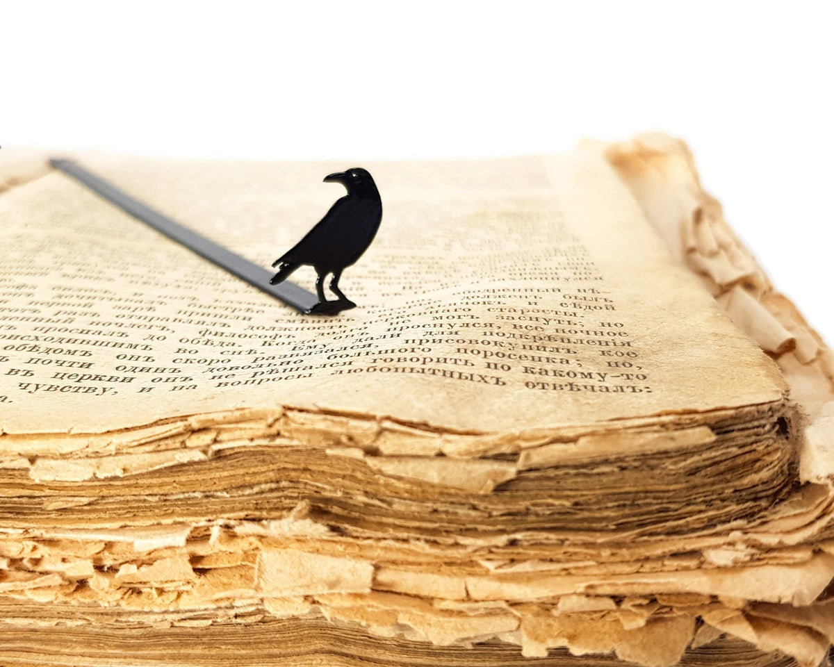 Raven metal bookmark marking a page in an open book