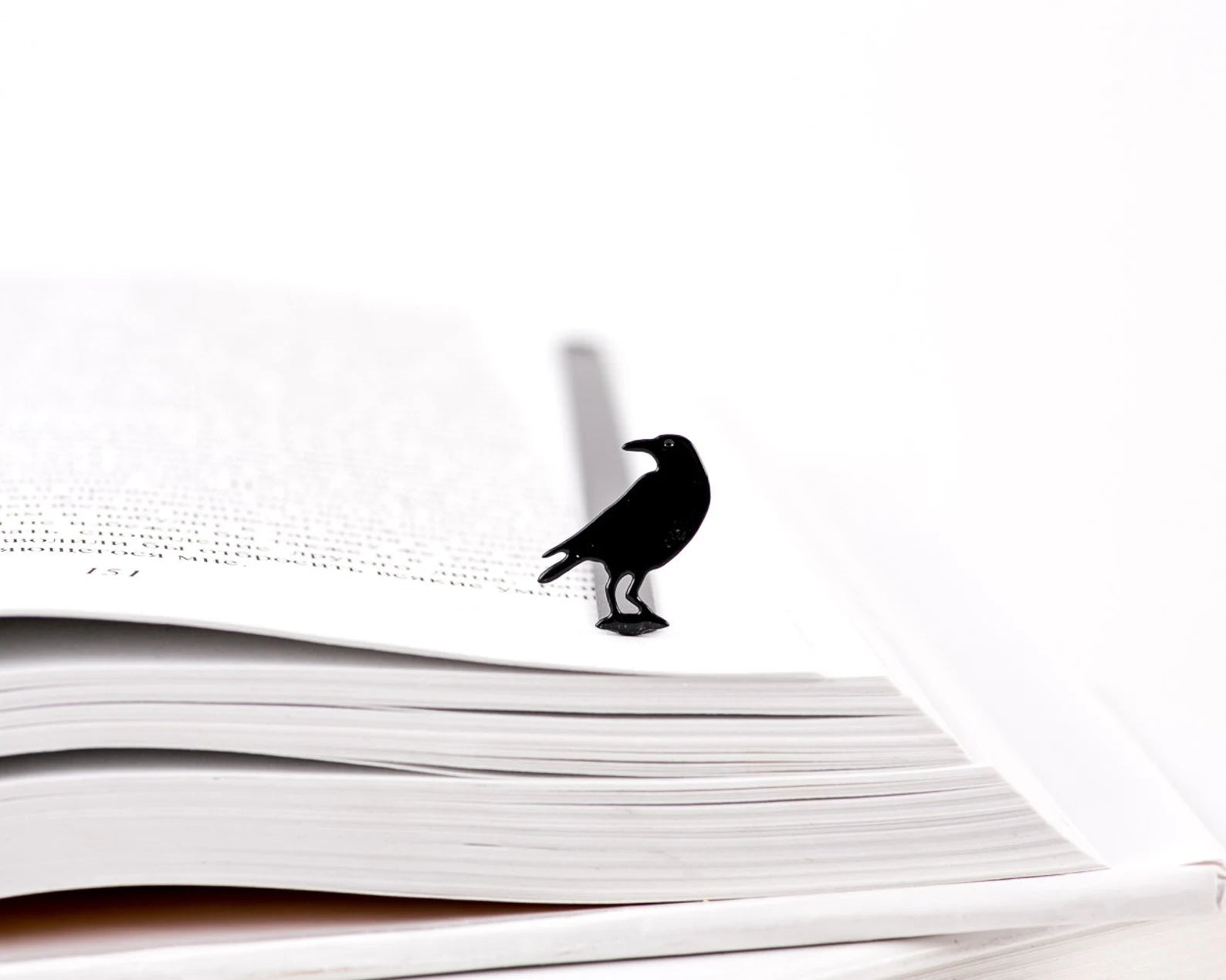 Raven metal bookmark resting on the pages of an open book