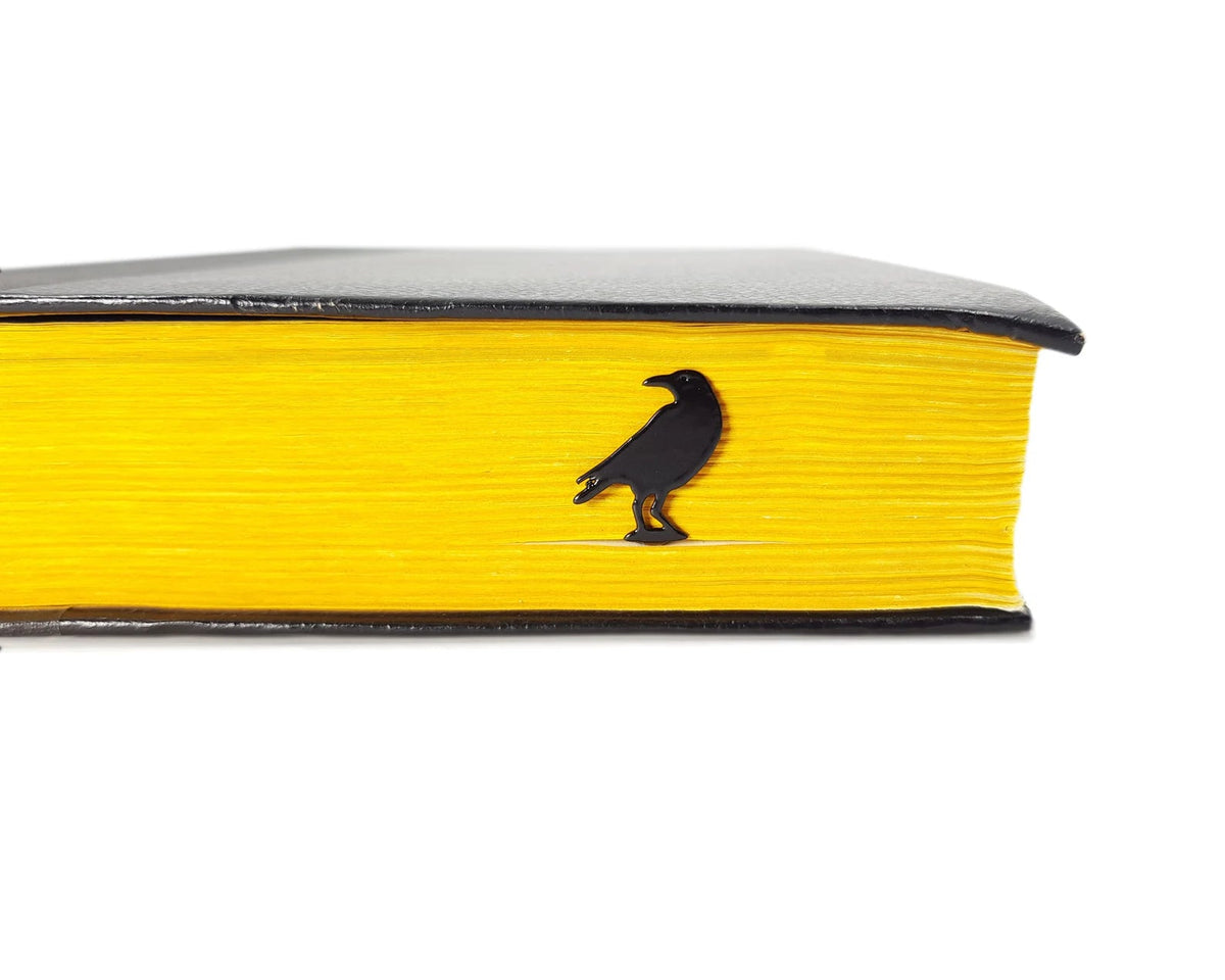Raven metal bookmark seen from the edge of a closed book