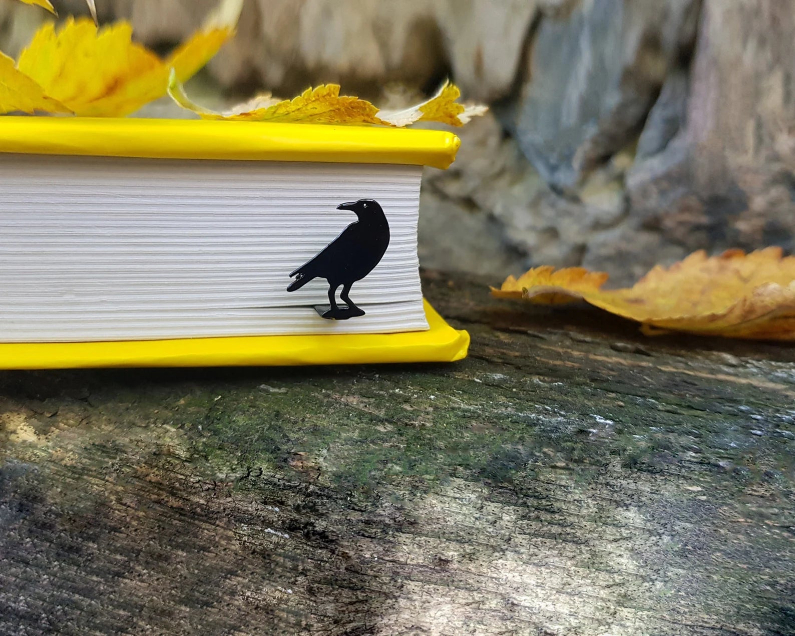 Raven metal bookmark clipped in a closed book, viewed from the side