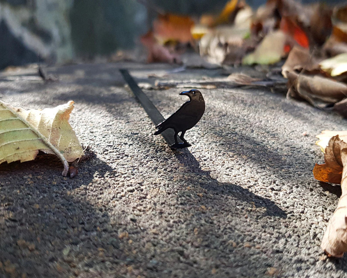 Raven metal bookmark — bookmark outdoors on stone path