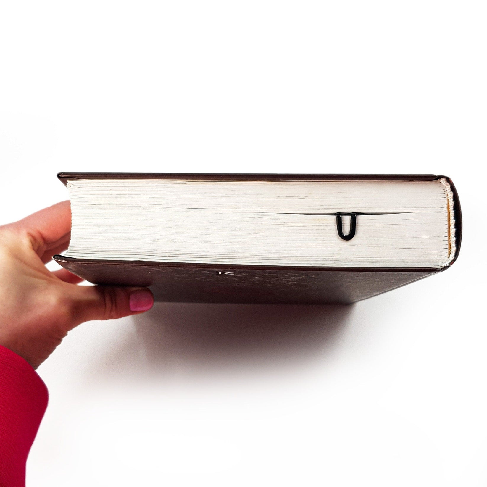 Read Here metal bookmark held in a hand to show its size