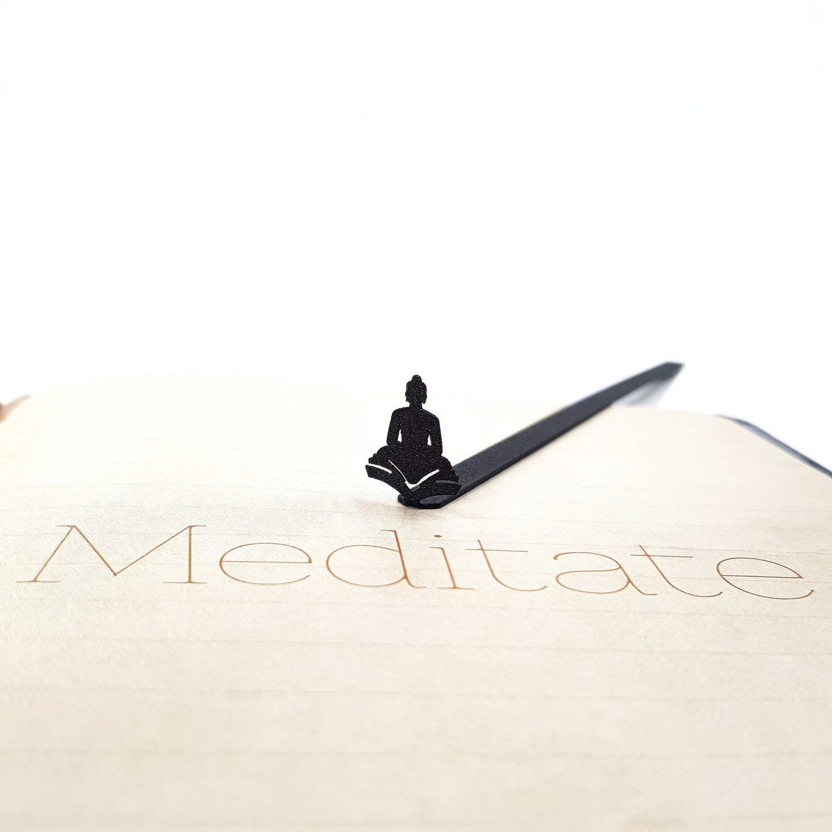Reading Buddha metal bookmark resting on the pages of an open book