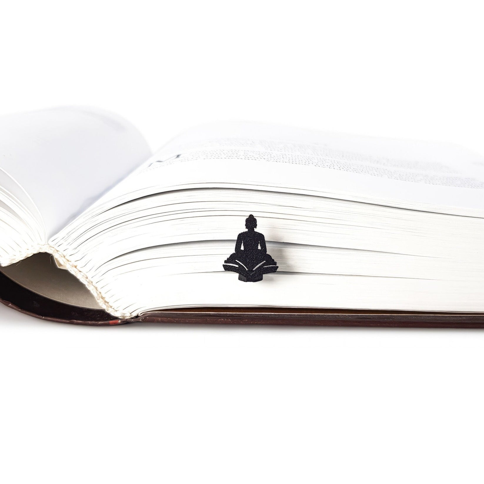 Reading Buddha metal bookmark lying across the pages of an open book