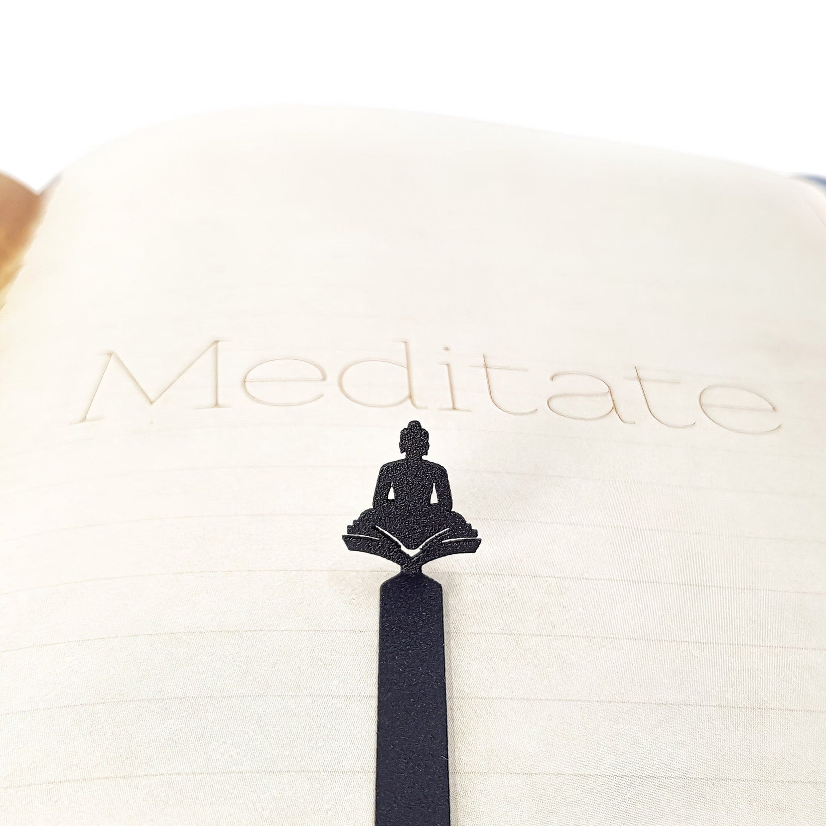 Reading Buddha metal bookmark set into the gutter of an open book