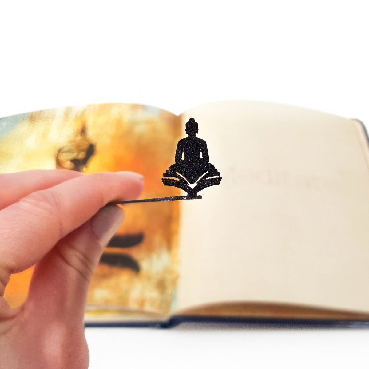 Reading Buddha metal bookmark marking a page in an illustrated book