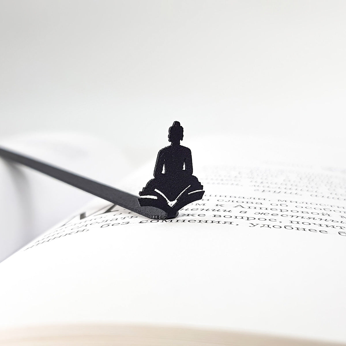 Reading Buddha metal bookmark marking a page in an open book