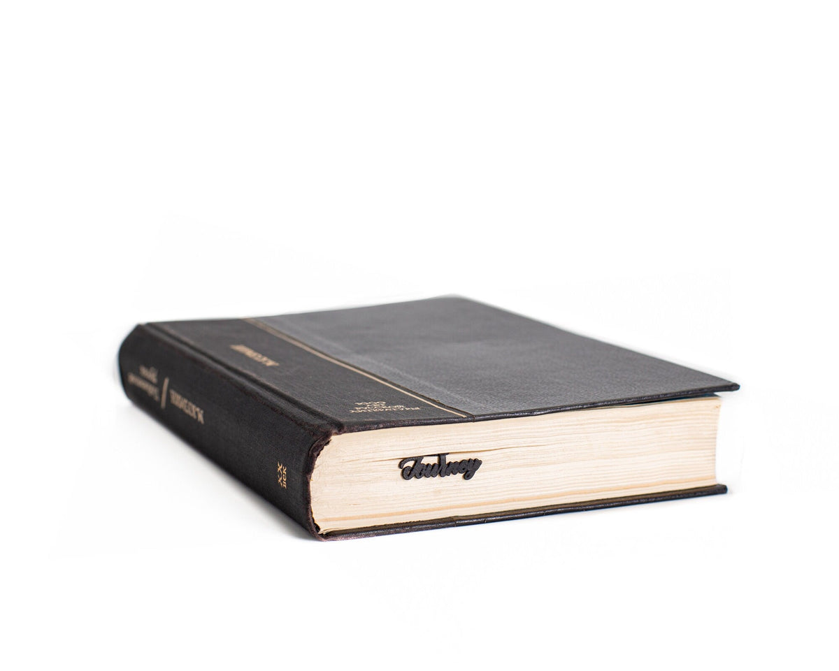 Reading Journey metal bookmark in a closed book, only its top showing above the pages