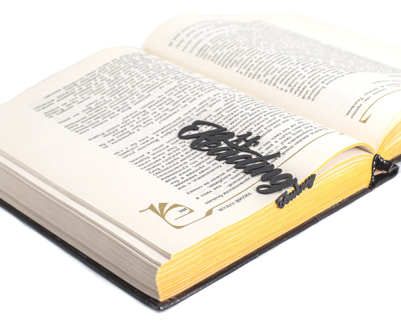 Reading Journey metal bookmark lying across the pages of an open book