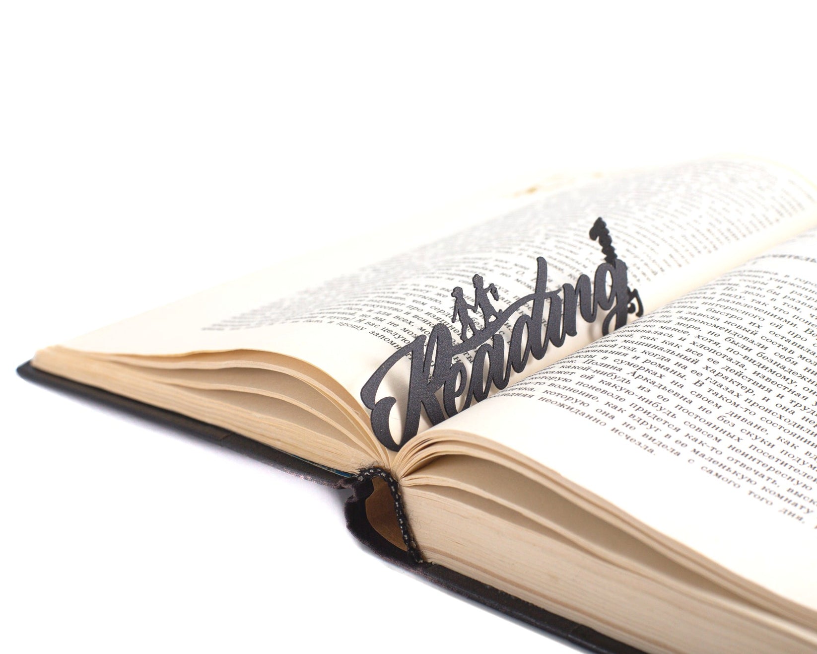Reading Journey metal bookmark resting on the pages of an open book