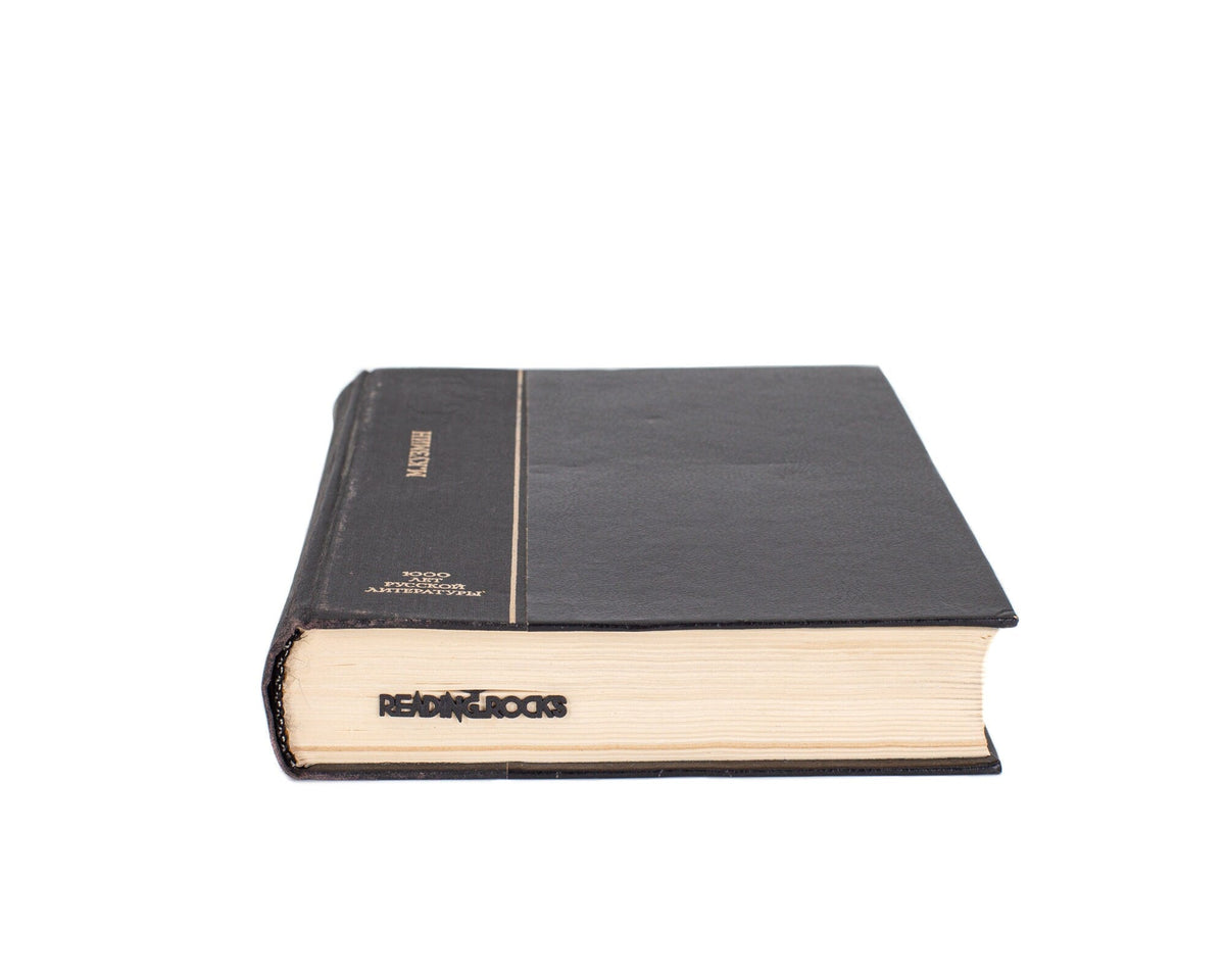 Reading Rocks metal bookmark in a closed book, only its top showing above the pages