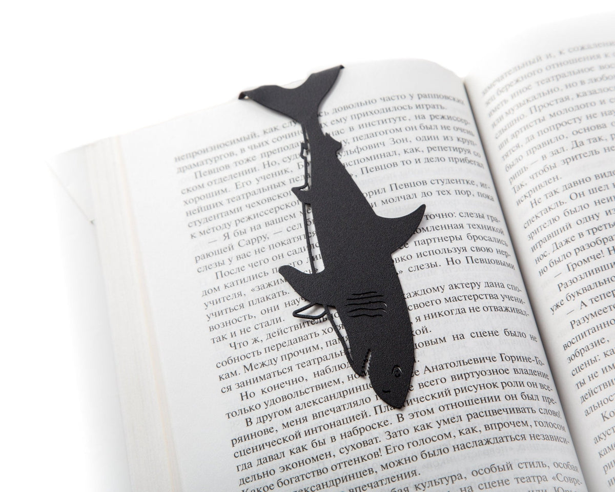 Reading Shark metal bookmark resting on the pages of an open book