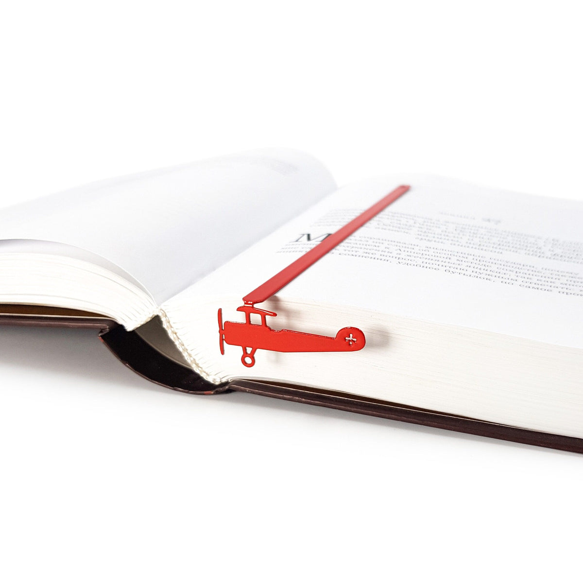 Red Biplane metal bookmark in red seen from the edge of a closed book