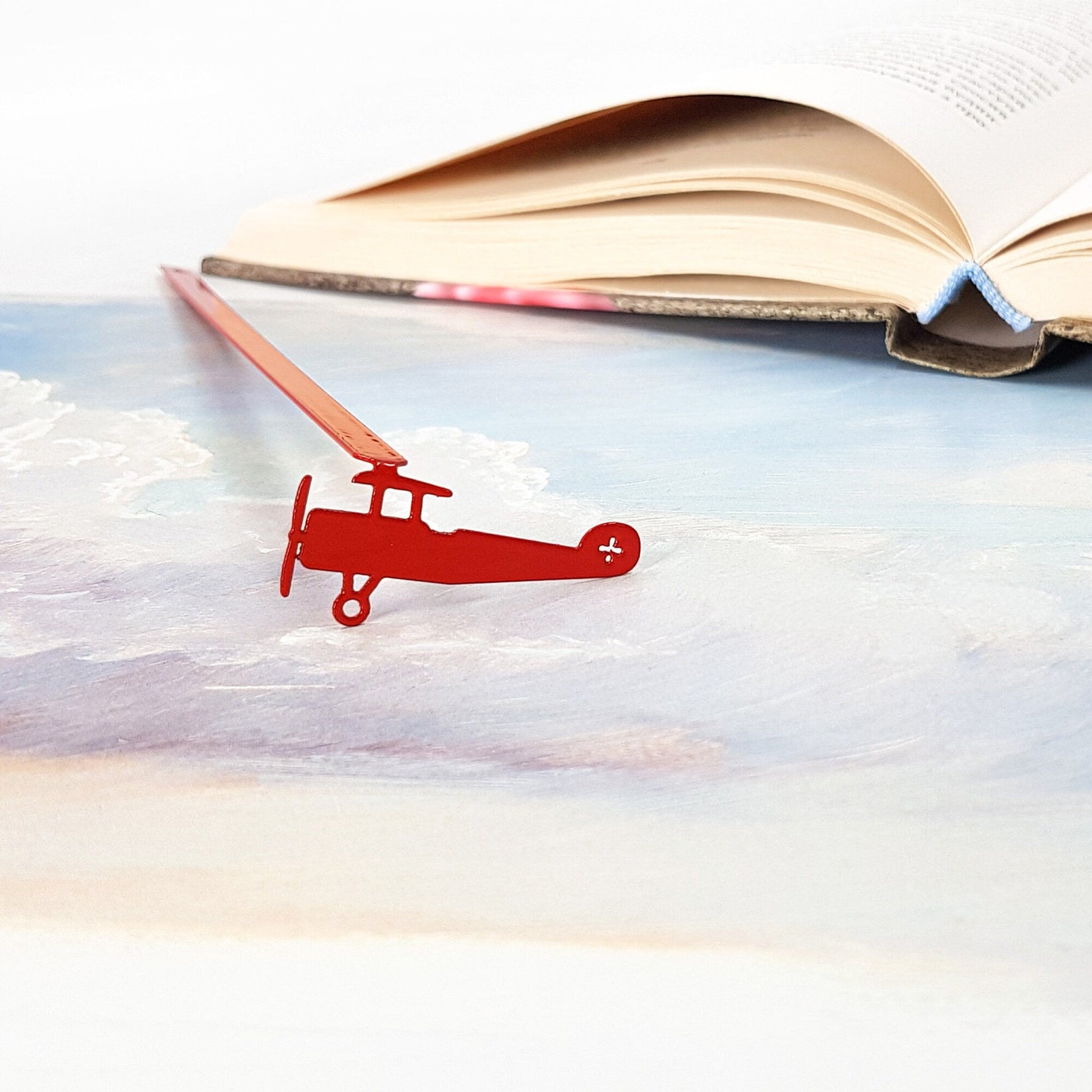 Red Biplane metal bookmark in red marking a page in an illustrated book