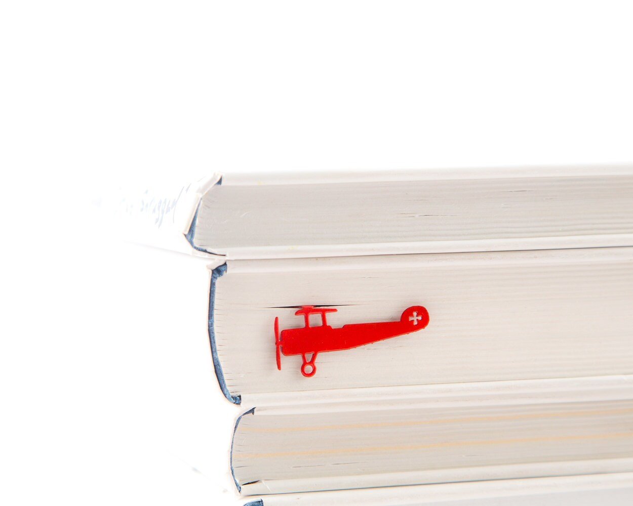 Red Biplane metal bookmark in red in a closed book, only its top showing above the pages