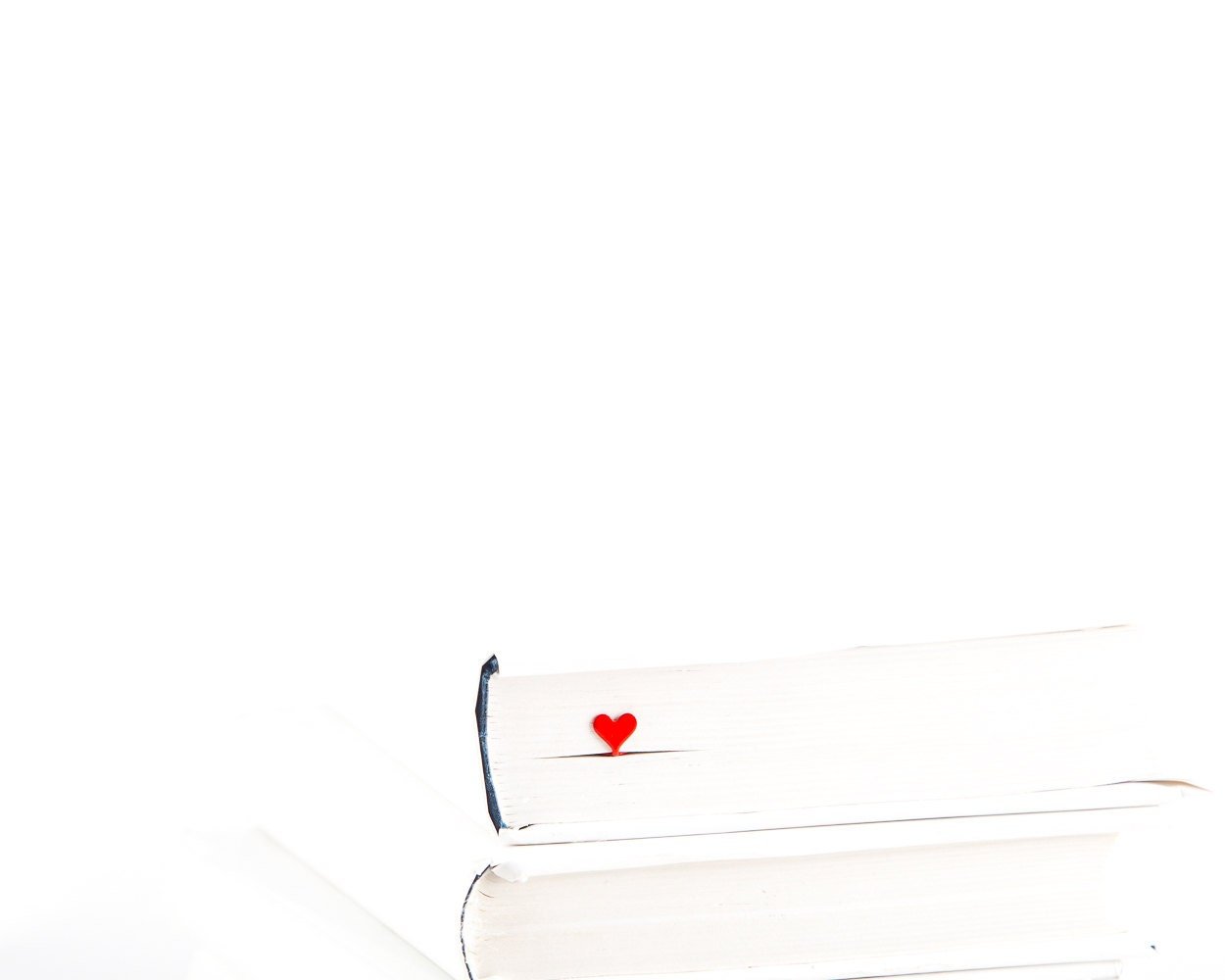 Red Heart metal bookmark in red in a closed book, only its top showing above the pages