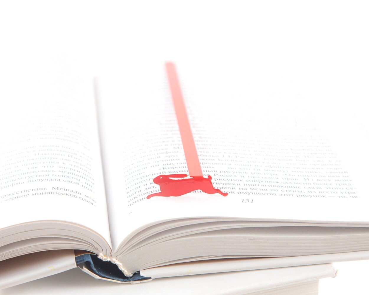 Red Rabbit metal bookmark in red resting on the pages of an open book