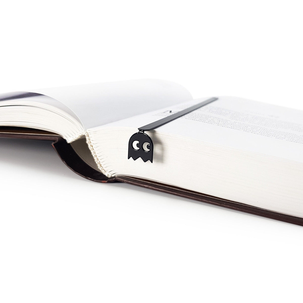 Retro Ghost metal bookmark marking a page in an open book
