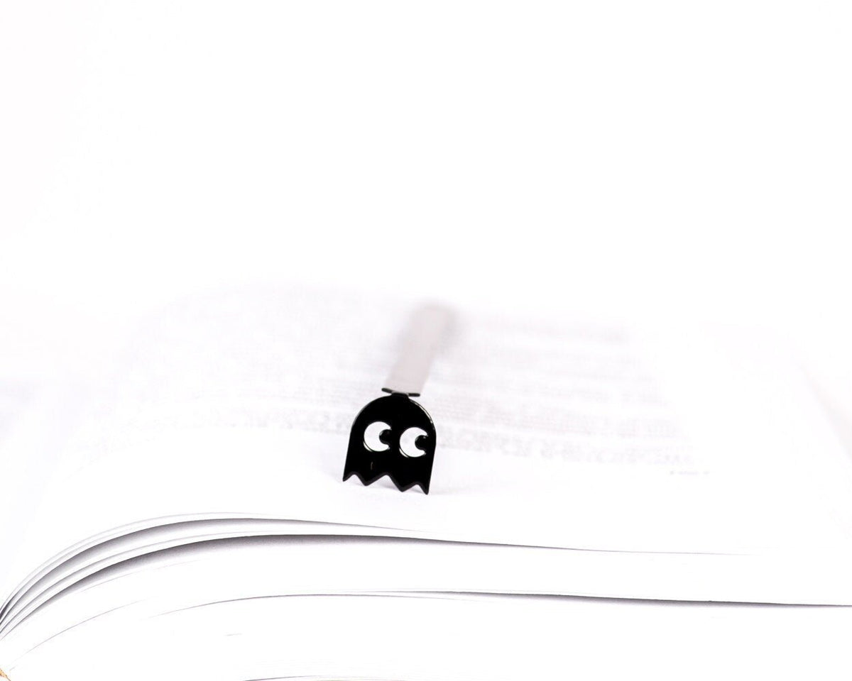 Retro Ghost metal bookmark resting on the pages of an open book