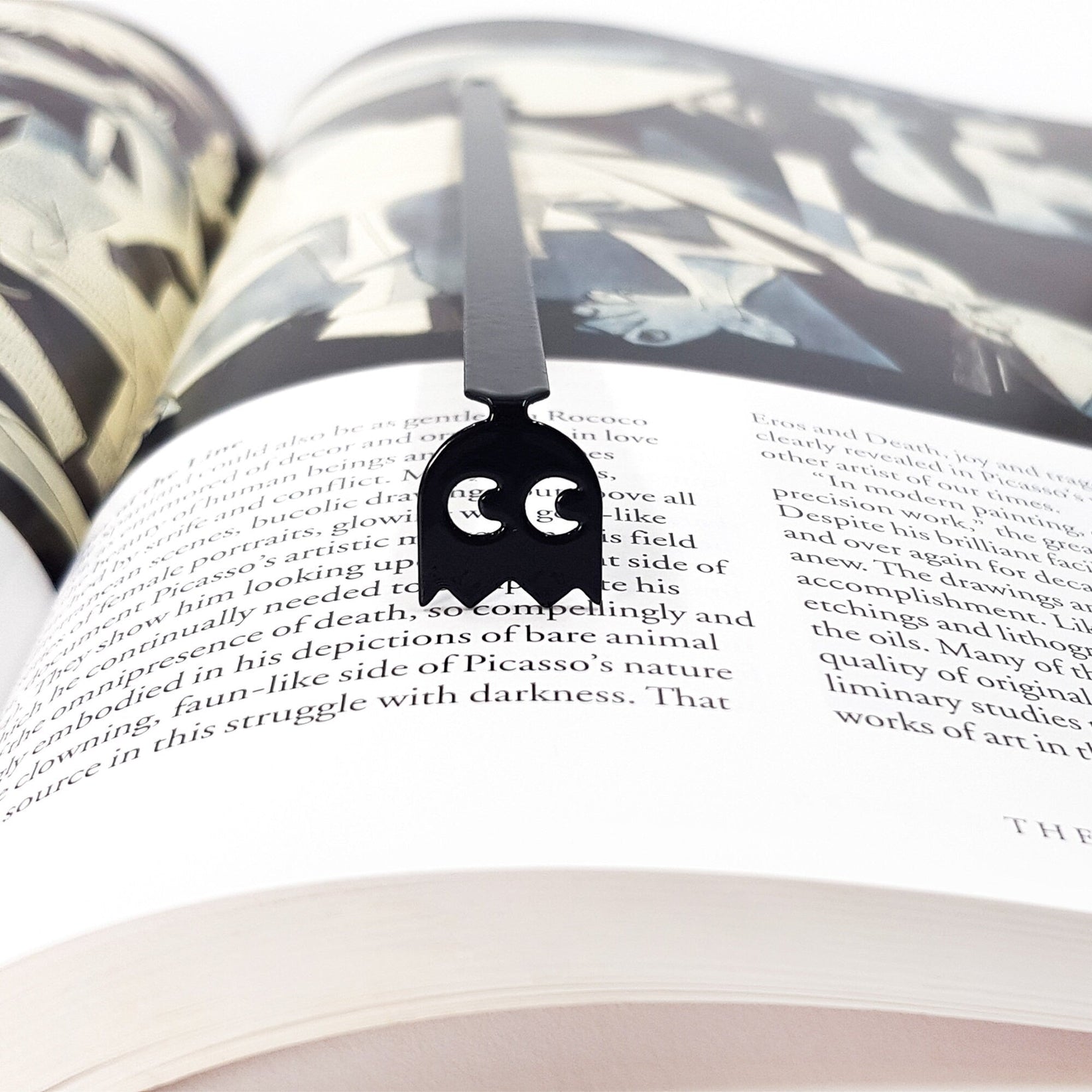 Retro Ghost metal bookmark lying across the pages of an open book