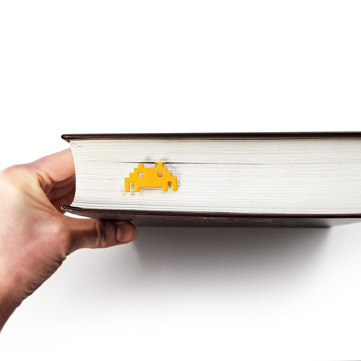 Retro Monster metal bookmark held up beside an open book