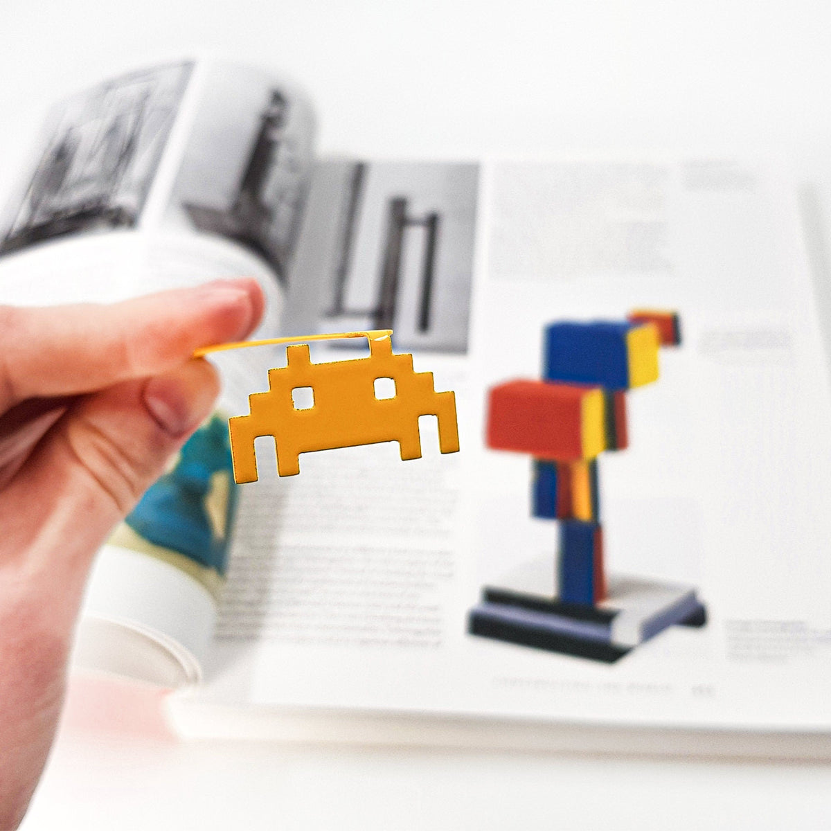 Retro Monster metal bookmark held in a hand above an open book