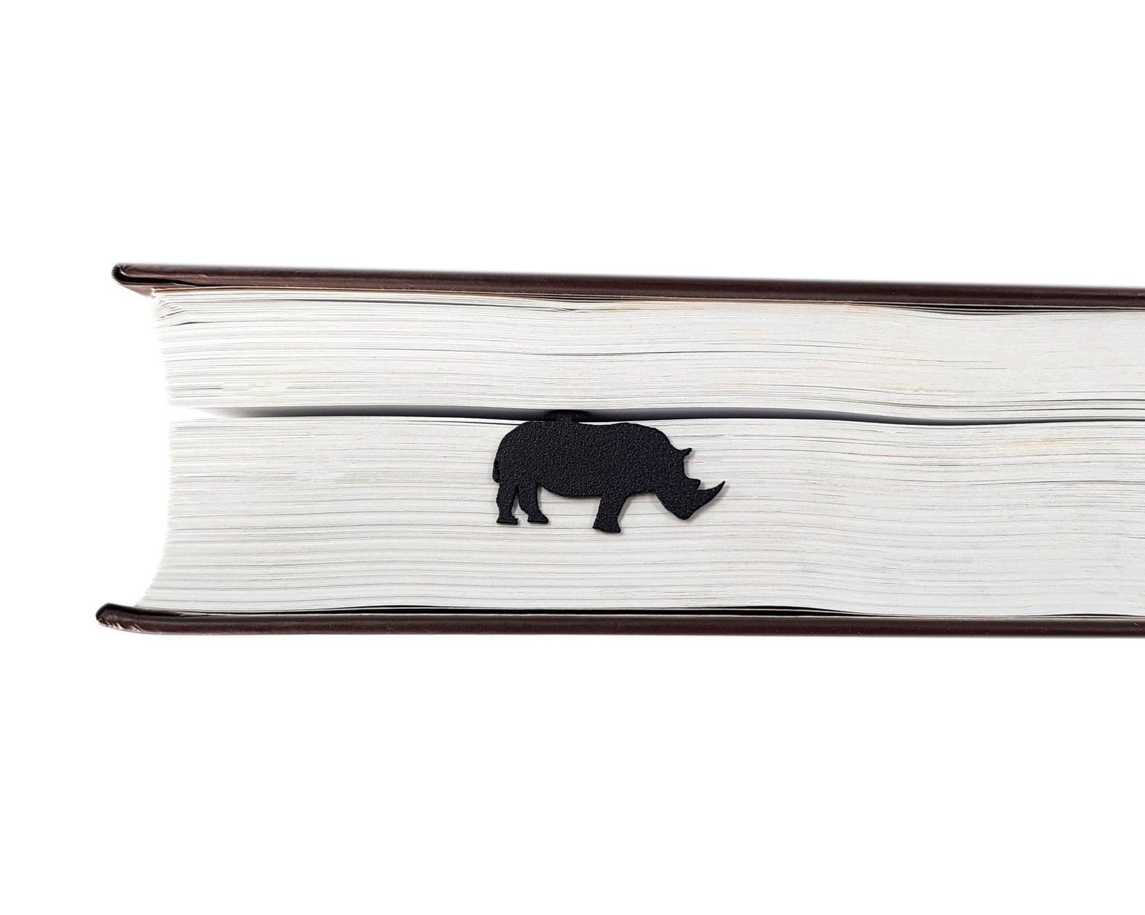 Rhinos metal bookmark in a closed book, only its top showing above the pages