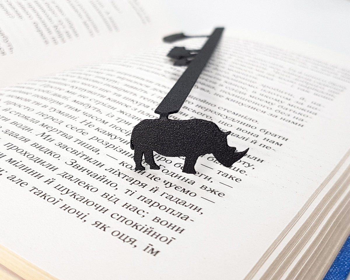 Rhinos metal bookmark resting on the pages of an open book, view 5