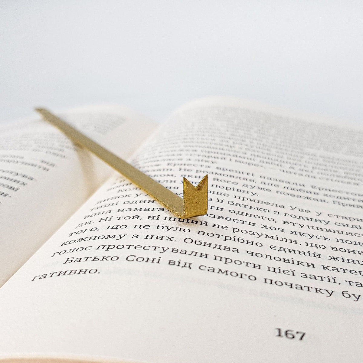 Ribbon metal bookmark in gold marking a page in an open book