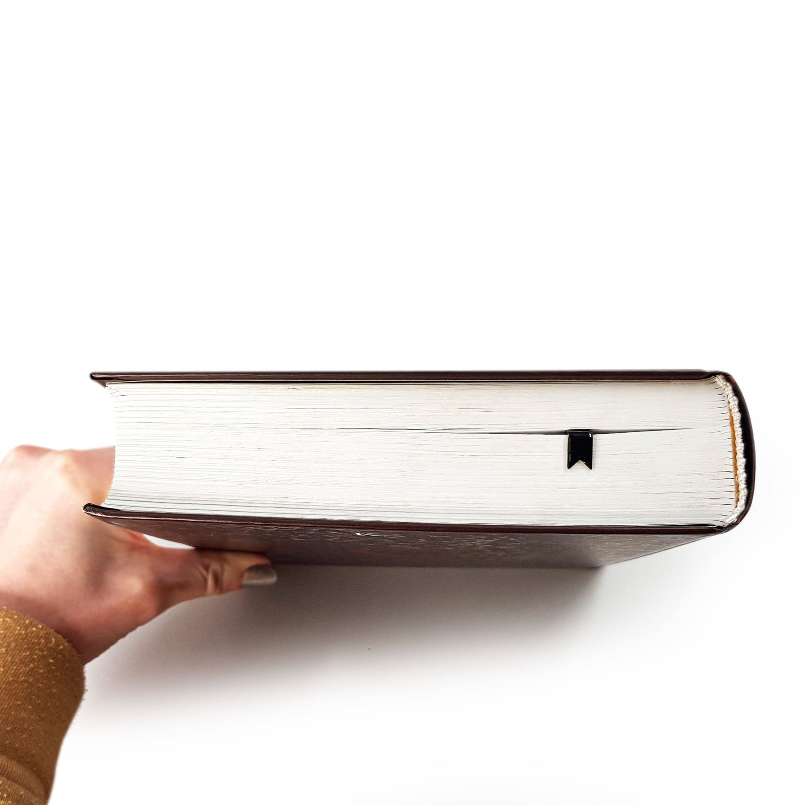 Ribbon metal bookmark held in a hand above an open book