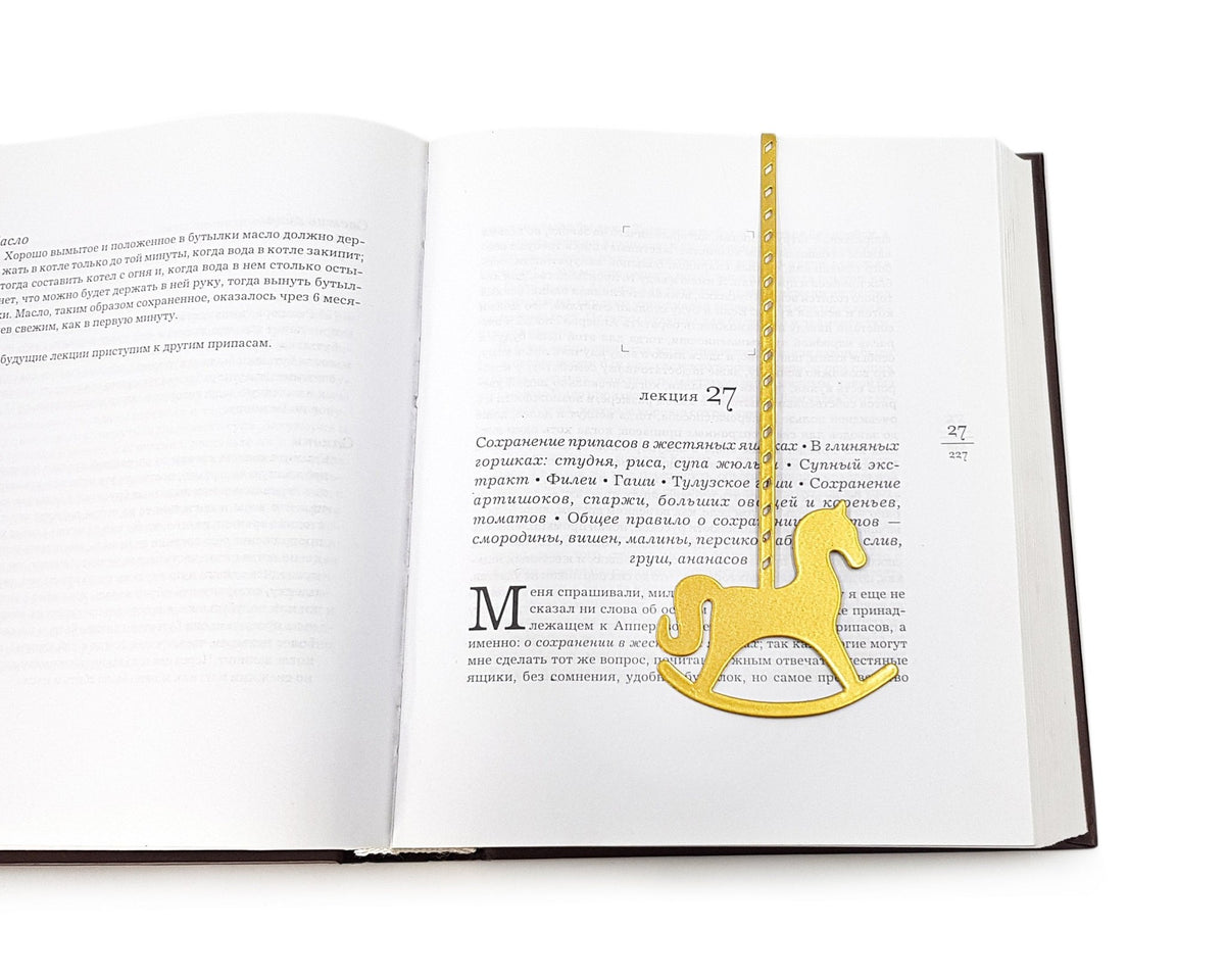 Rocking Horse metal bookmark in gold lying across the pages of an open book