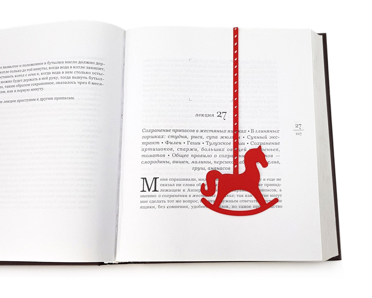 Rocking Horse metal bookmark in red set into the gutter of an open book