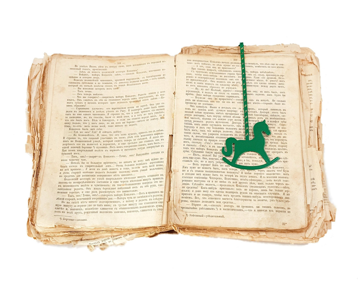 Rocking Horse metal bookmark in green marking a page in an open book