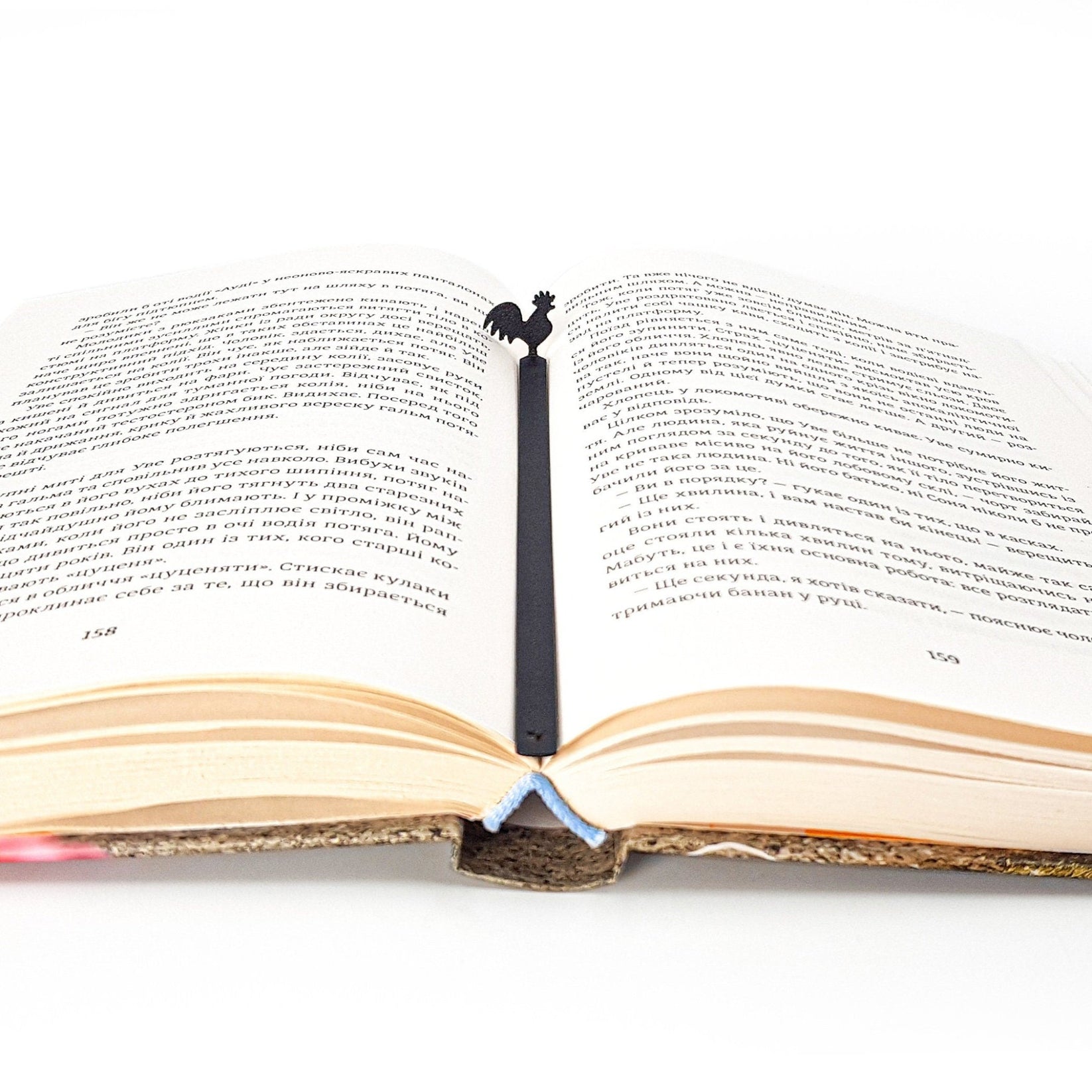 Rooster metal bookmark resting on the pages of an open book