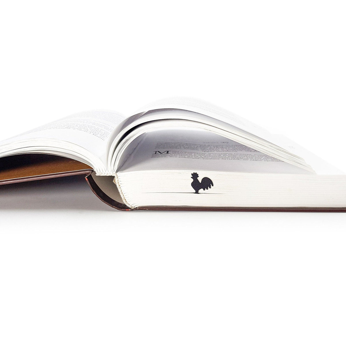 Rooster metal bookmark marking a page in an open book