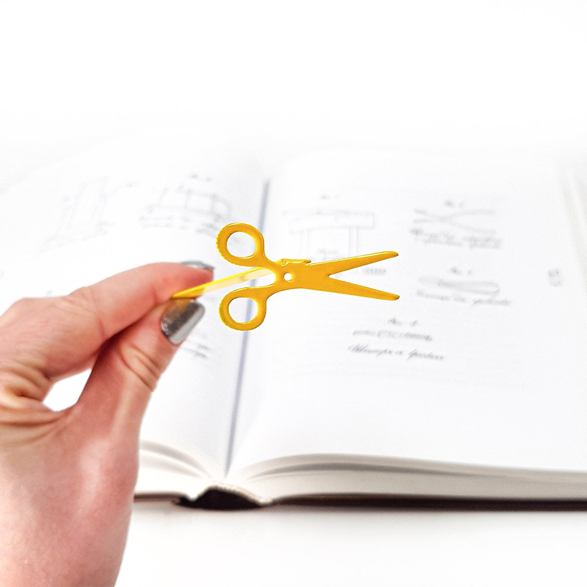 Scissors metal bookmark in gold marking a page in a notebook