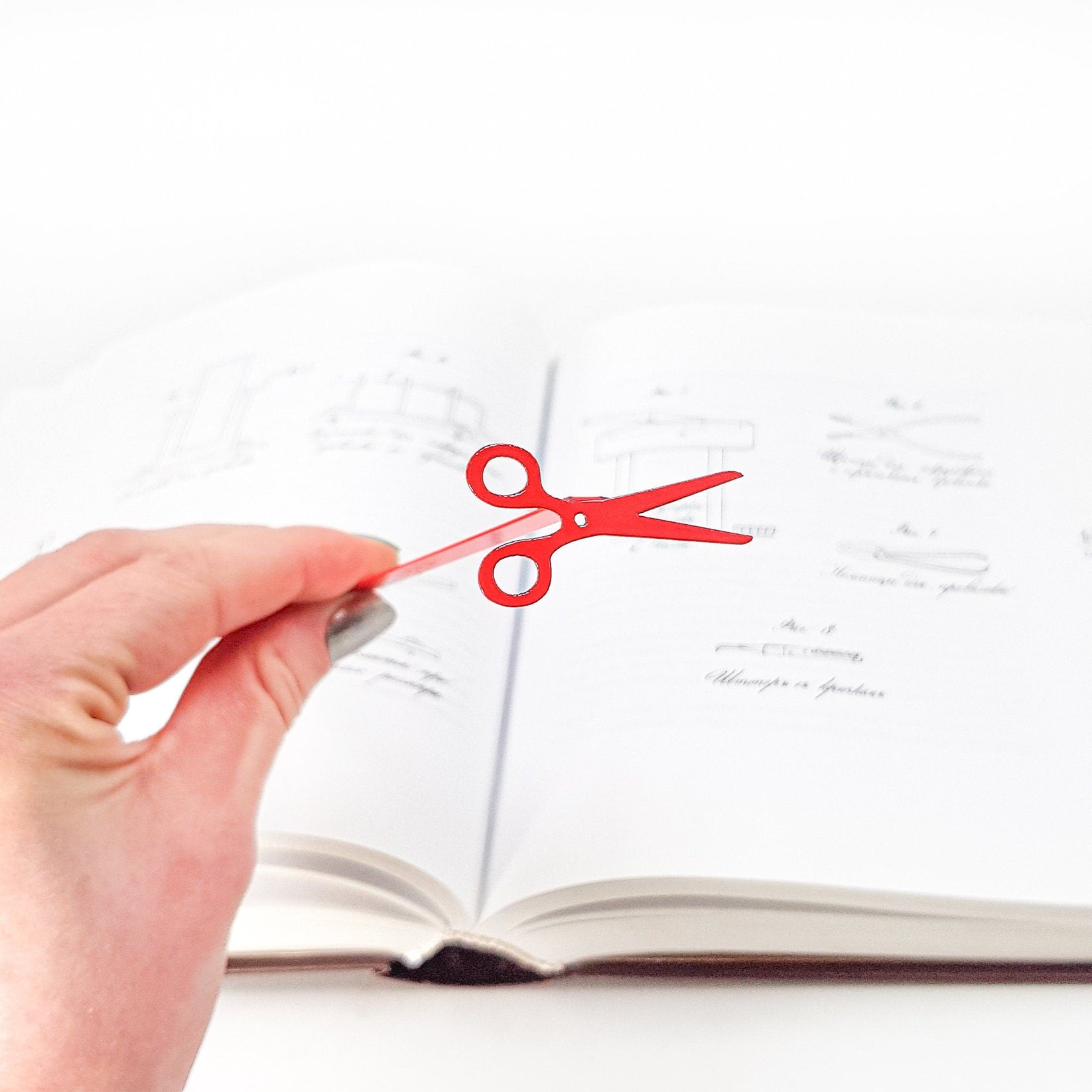 Scissors metal bookmark in red tucked into a notebook