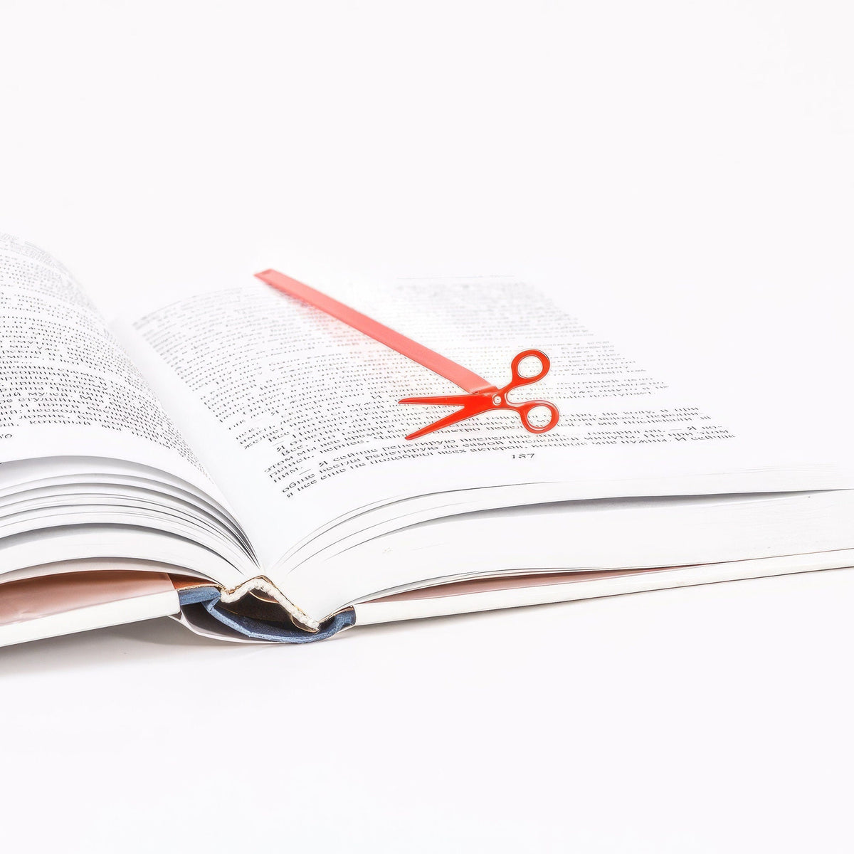 Scissors metal bookmark in red resting on the pages of an open book