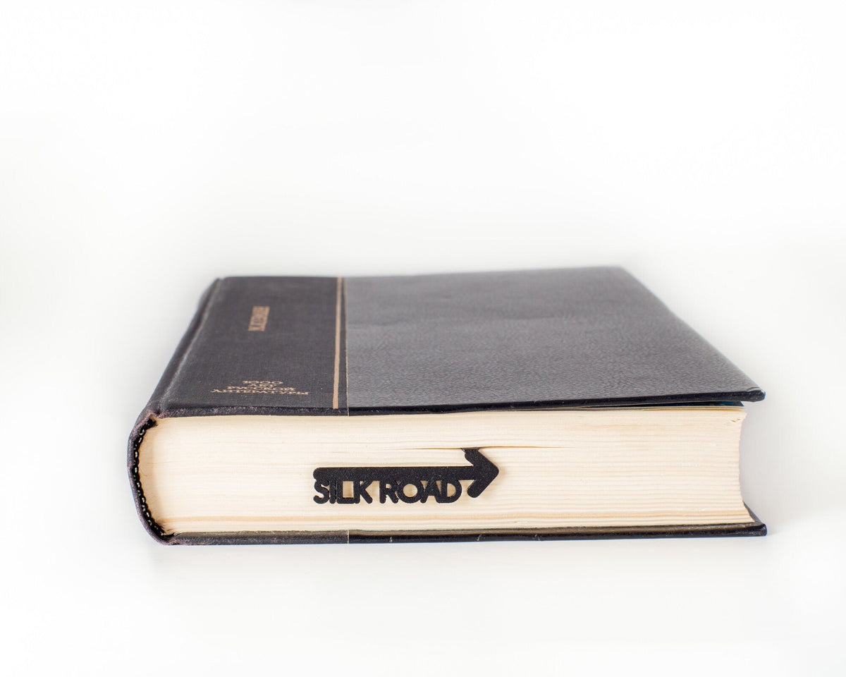 Silk Road metal bookmark in a closed book, only its top showing above the pages