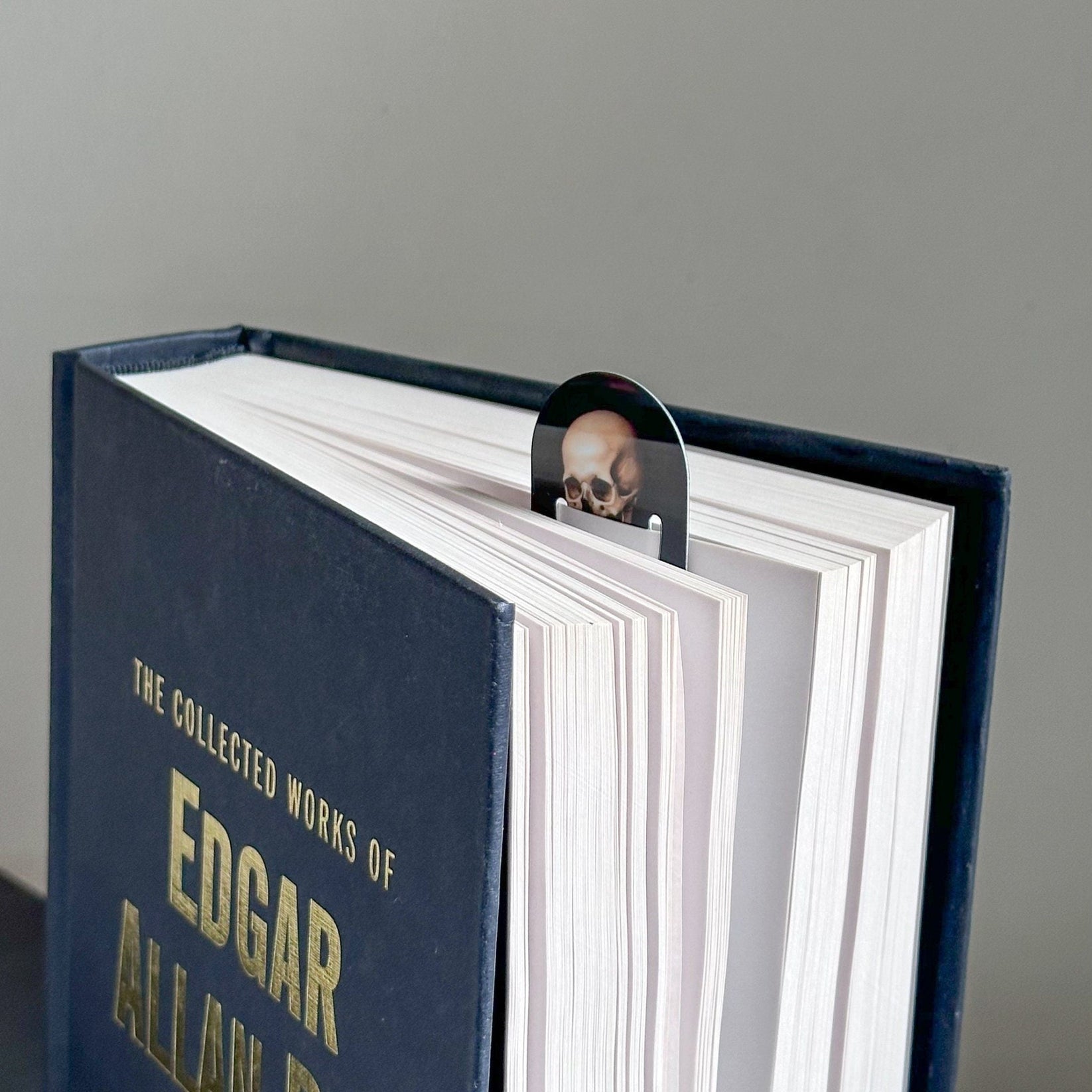Skeleton with the Book metal bookmark in a closed book, only its top showing above the pages