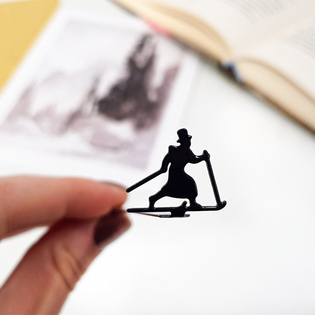 Skier in High Hat metal bookmark marking a page in an illustrated book