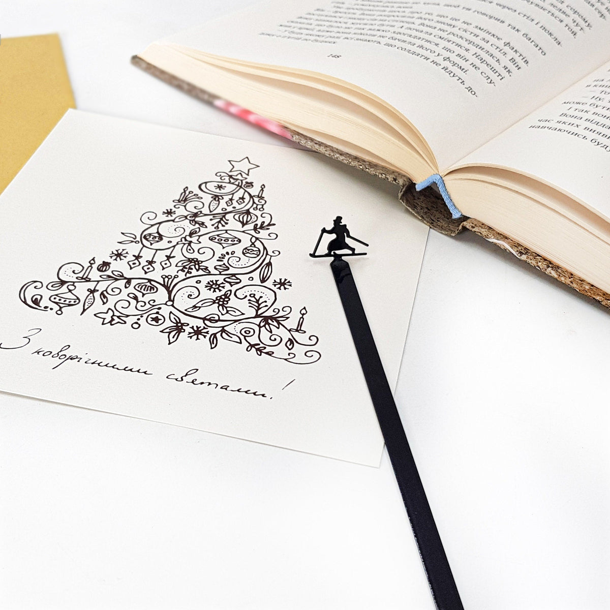 Skier in High Hat metal bookmark on an illustrated page