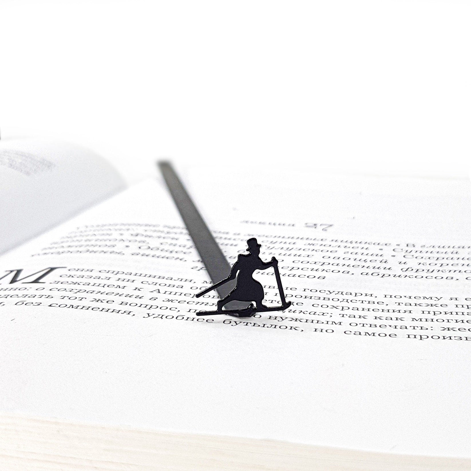 Skier in High Hat metal bookmark lying across the pages of an open book