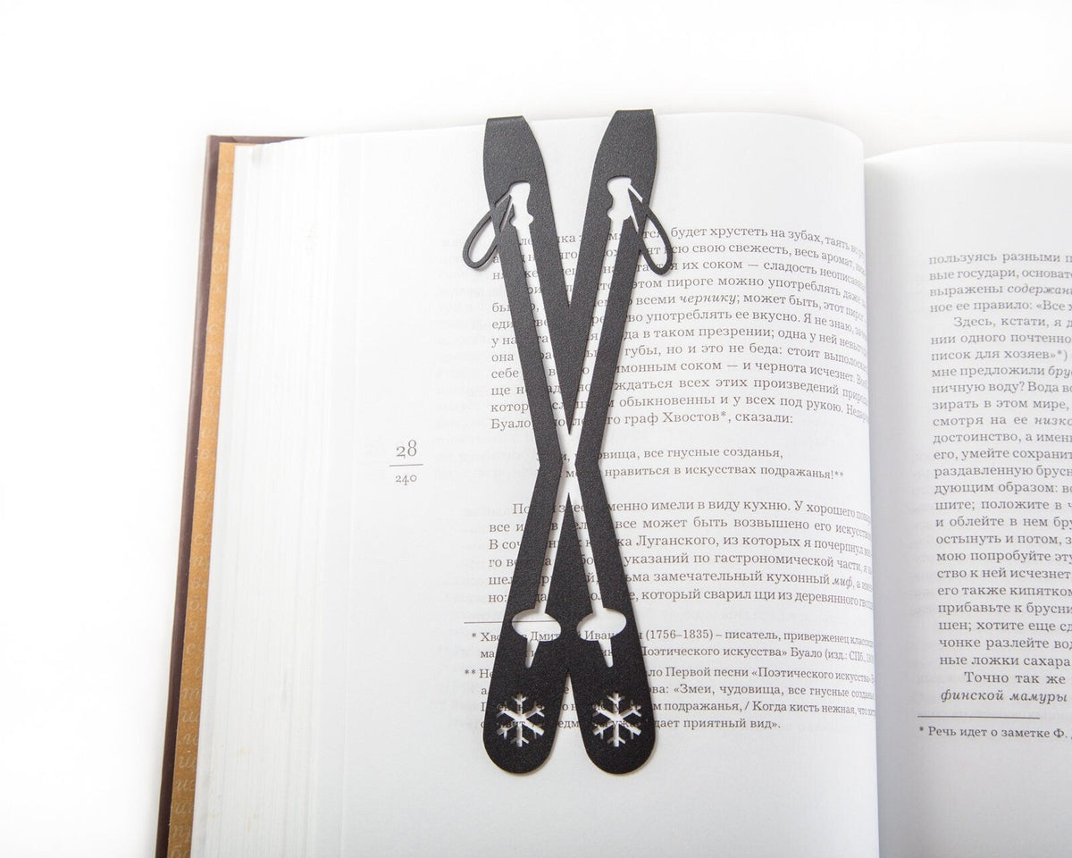 Skis metal bookmark marking a page in an open book